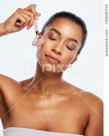 Skin care, facial roller and massage for a woman in studio for dermatology, cosmetic and natural face. Aesthetic model person with spa jade stone tools for healthy glow isolated on a white background 130606558