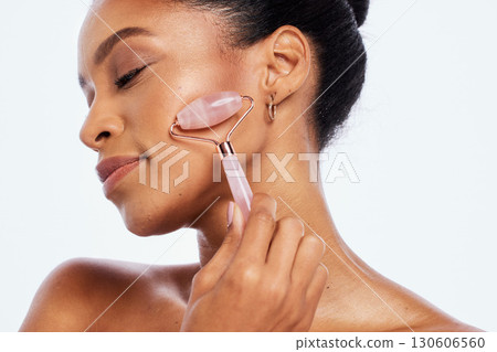 Facial roller, beauty and face of a woman in studio for dermatology, cosmetics and natural skin. Aesthetic model person with facial massage tools for healthy glow isolated on a white background Facial roller, beauty and face of a woman in studio for dermatology, cosmetics and natural skin. Aesthetic model person with facial massage tools for healthy glow isolated on a white background 130606560