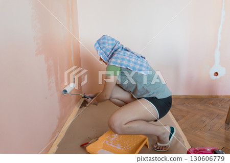 Woman Painting Peach Wall Interior with Roller: Home Renovation, DIY Project, Soft Color Scheme, Modern Style, Interior Design, Female Painter Woman Painting Peach Wall Interior with Roller: Home Renovation, DIY Project, Soft Color Scheme, Modern Style, Interior Design, Female Painter 130606779