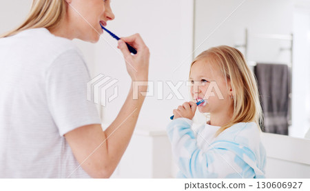 Mom, girl and brushing teeth together in bathroom, learning and support with foam for wellness in family house. Toothbrush, mother and daughter with toothpaste, teaching and care for cleaning mouth Mom, girl and brushing teeth together in bathroom, learning and support with foam for wellness in family house. Toothbrush, mother and daughter with toothpaste, teaching and care for cleaning mouth 130606927