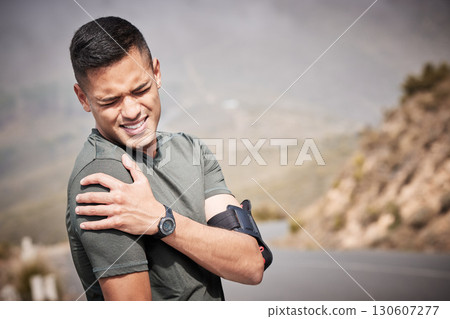 Fitness, injury and mockup with a sports man holding his shoulder in pain while running outdoor. Medical, exercise and anatomy with a male runner or athlete suffering from a hurt joint while training 130607277