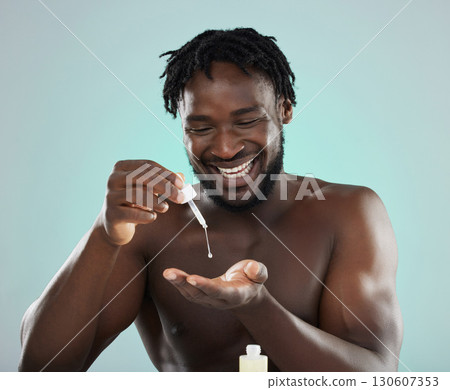 Man, face serum and happy about skincare, beauty and self care product in studio. Healthy black person on blue background for facial oil, dermatology and cosmetics for skin glow, health and wellness Man, face serum and happy about skincare, beauty and self care product in studio. Healthy black person on blue background for facial oil, dermatology and cosmetics for skin glow, health and wellness 130607353