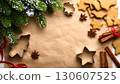 Christmas homemade decoration and sweets set. Green spruce, gingerbreads, cookie cutters, anise stars, cinnamon sticks on baking paper, copy space. 130607525