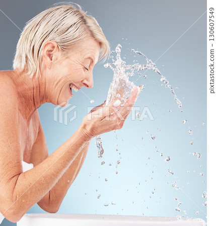 Senior woman, cleaning face and water splash on studio background for beauty, wellness and shower. Happy model, facial skincare drops and washing in bathroom for aesthetic, cosmetics and healthy body 130607549
