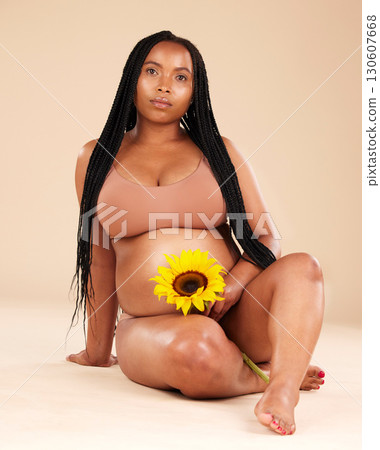 Black woman sitting with flower, pregnant in portrait and beauty with skincare isolated on studio background. Pregnancy glow, mother and nature with natural cosmetic care, health and wellness 130607668