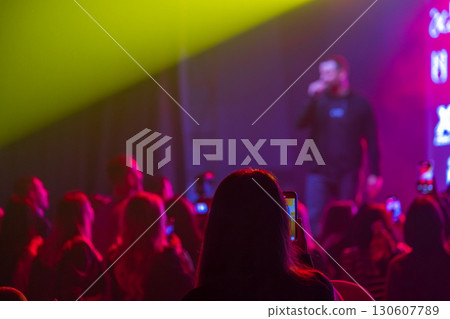 Audience enjoying live music performance under vibrant lights at a night concert 130607789