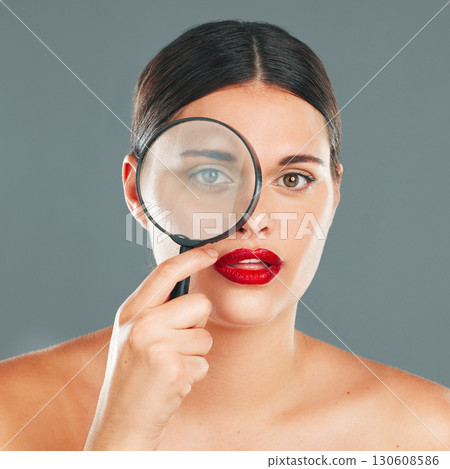 Portrait, magnifying glass and eye with a model woman in studio on a gray background for beauty or skincare. Face, makeup and search with an attractive young woman checking her skin for cleaning Portrait, magnifying glass and eye with a model woman in studio on a gray background for beauty or skincare. Face, makeup and search with an attractive young woman checking her skin for cleaning 130608586