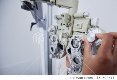 Eye exam, vision and hands of optometrist with patient in clinic for test, eyesight and optical assessment. Optometry, healthcare and optician with woman in phoropter, medical machine and lens 130608751