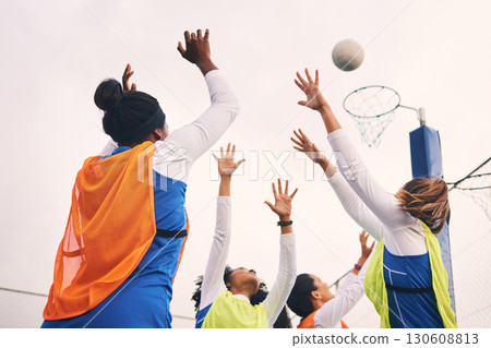 Netball, goal shooting and fitness of a girl athlete group on an outdoor sports court. Aim, sport game and match challenge of a black person with a ball doing exercise and training in a competition 130608813
