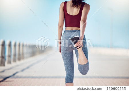 Fitness, woman and stretching legs at beach promenade for exercise, wellness and training. Back of athlete, runner and person warm up body at seaside for summer workout, sports and marathon running 130609235