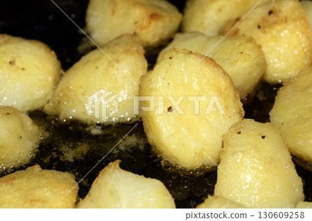 Close up of delicious fresh roast potatoes cooking in fat oil close up Close up of delicious fresh roast potatoes cooking in fat oil close up 130609258