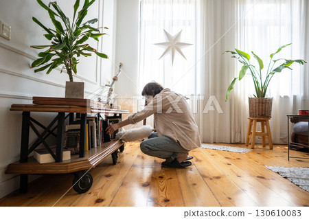 Dust removal from neglected areas at home. Busy woman use duster for cleaning of bookshelves Dust removal from neglected areas at home. Busy woman use duster for cleaning of bookshelves 130610083