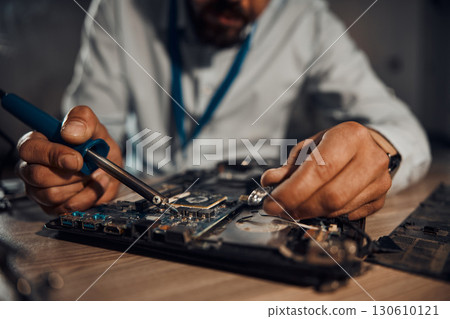 Man hands, it or soldering motherboard in engineering workshop for night database fixing. Zoom, technician or circuit board tools in repair, maintenance or upgrade in information technology industry Man hands, it or soldering motherboard in engineering workshop for night database fixing. Zoom, technician or circuit board tools in repair, maintenance or upgrade in information technology industry 130610121