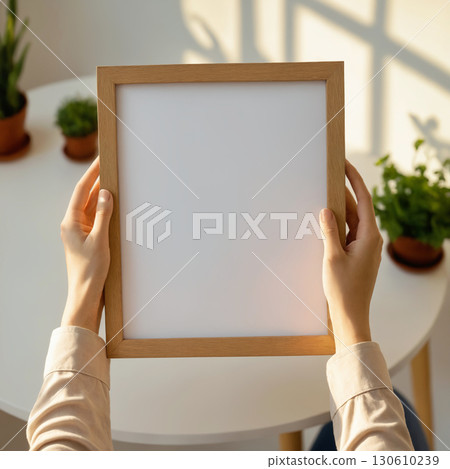 Empty picture frame in hands. Stylish wooden photoframe 130610239