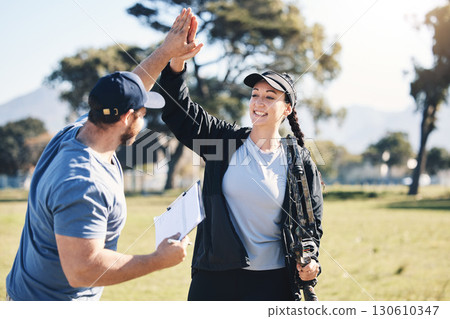 Woman, archery and personal trainer high five in sports for partnership, success or celebration on the grass field. Happy sporty female smile and touching hand of male coach for archer sport training 130610347