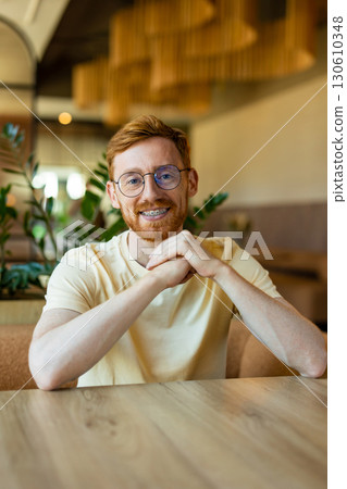 Smiling resting arms on table in cozy cafe interior waiting his order Smiling resting arms on table in cozy cafe interior waiting his order 130610348