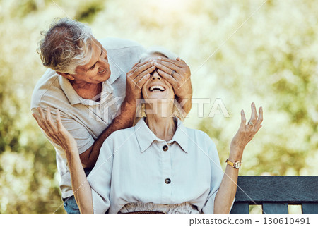 Retirement, love and surprise with a senior man covering the eyes of his wife from behind in the park. Happy, smile or date with a mature husband and a surprised woman in a garden during summer 130610491