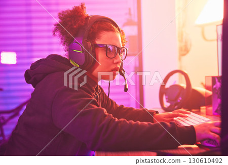 Computer games, young girl and headset in home for esports, online rpg and virtual competition. Female gamer, internet streamer and gaming on headphones in neon lighting, live streaming tech or gen z 130610492