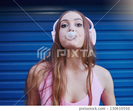 Young woman, bubblegum and headphones, face isolated on blue background, listen to music with freedom and fashion. Blowing bubble, candy and crazy gen z youth in studio, fun with radio or audio tech Young woman, bubblegum and headphones, face isolated on blue background, listen to music with freedom and fashion. Blowing bubble, candy and crazy gen z youth in studio, fun with radio or audio tech 130610508