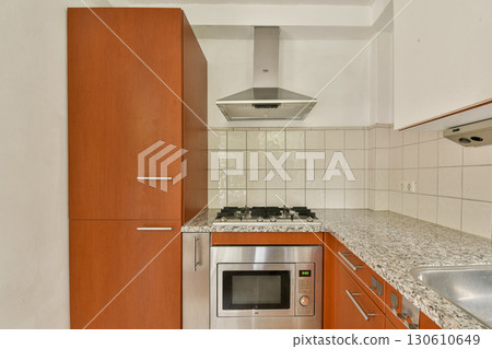 A contemporary kitchen featuring sleek cabinetry, a stainless steel oven, and a stylish cooktop, creating an inviting cooking space. 130610649