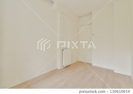 A spacious, minimalist room featuring plain white walls and wooden flooring, exuding simplicity and tranquility. Ideal for modern living concepts. 130610654