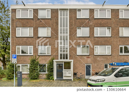 A modern residential structure featuring attractive brickwork, large windows, and well-maintained surroundings including greenery and parking. 130610664