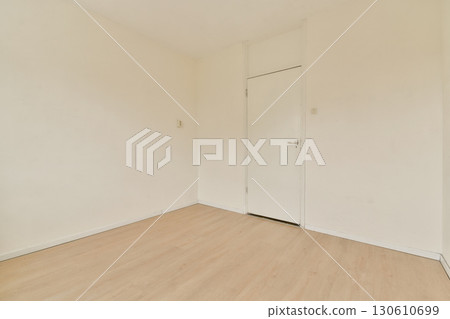 An empty room featuring bare walls and light wooden flooring, showcasing a minimalist aesthetic with ample natural light and simplicity throughout the space. 130610699