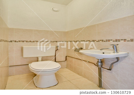 A clean and modern bathroom featuring a toilet and a sink. The tilework showcases a stylish design that enhances the overall aesthetic of the space. A clean and modern bathroom featuring a toilet and a sink. The tilework showcases a stylish design that enhances the overall aesthetic of the space. 130610729