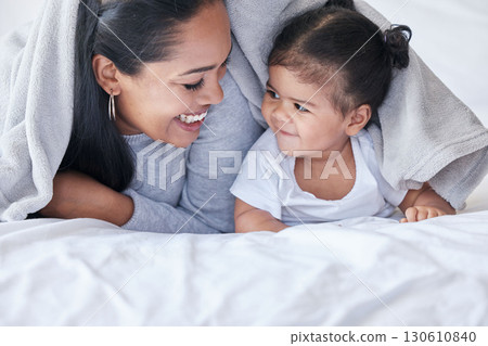 Happy, morning and mother with a baby and blanket for comfort, relaxing and laughing together. Smile, cute and mom resting in bed with a child while bonding, playing and quality time with a kid 130610840