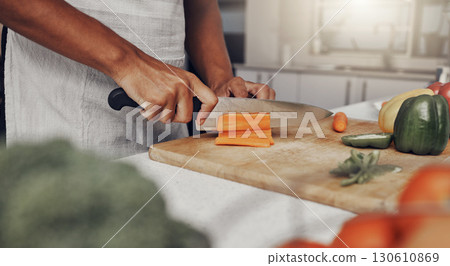 Hands, food and nutrition with a man cooking in the kitchen while cutting vegetables on a wooden chopping board. Salad, health or diet with a chef preparing a meal while standing alone in his home 130610869