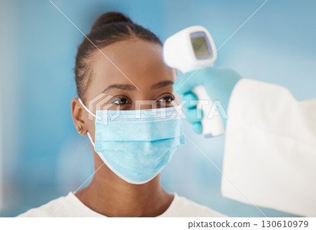 Temperature, healthcare and black woman with covid test for medical safety, consultation and health. Thermometer, sick and African girl with a face mask for a virus and hand of a doctor to check 130610979