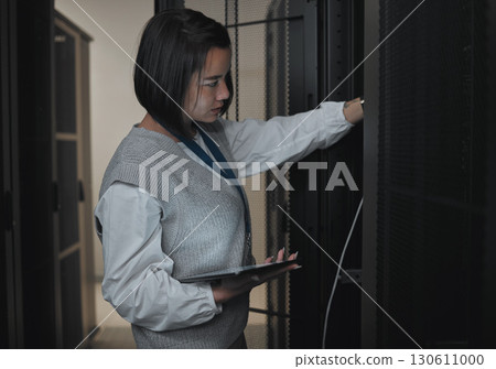 Tablet, server room and engineering with a programmer asian woman at work on a computer mainframe. Software, database and information technology with a female coder working alone on a cyber network 130611000