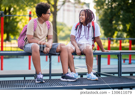 Teens sitting at the playground after school and talking Teens sitting at the playground after school and talking 130611079