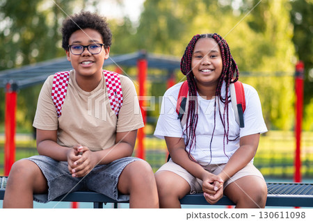 Teens sitting at the playground after school and talking Teens sitting at the playground after school and talking 130611098