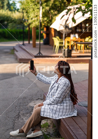 Woman posing with phone in hands doing selfie or making video call 130611133