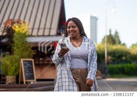 Curvy woman checking smartphone while walking outdoors Curvy woman checking smartphone while walking outdoors 130611137