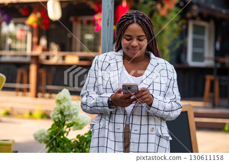 African American plus size woman looking at smartphone outdoors African American plus size woman looking at smartphone outdoors 130611158