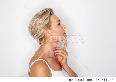 Side profile mature blonde woman with short hair, touching chin, isolated on white background. Concept of beauty, skincare, anti-aging, wellness, mindfulness Side profile mature blonde woman with short hair, touching chin, isolated on white background. Concept of beauty, skincare, anti-aging, wellness, mindfulness 130611222