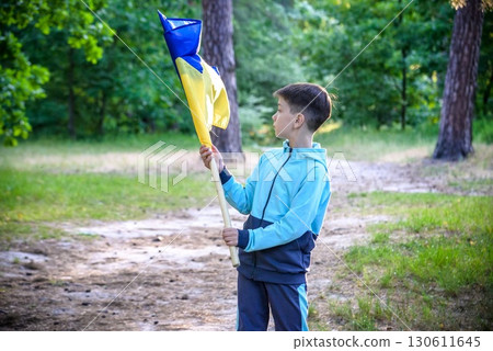 Ukrainian boy with waving flag and praying to stop the war in Uk 130611645