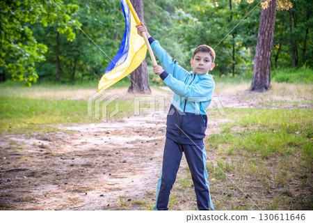 Ukrainian boy with waving flag and praying to stop the war in Ukraine in a field at sunset. War of Russia against Ukraine. Stop War 130611646