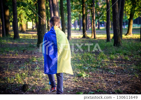Worried teenager patriot wear blue yellow Ukrainian flag on his shoulders. Spring nature background. Ukraine national symbol. Patriotism Worried teenager patriot wear blue yellow Ukrainian flag on his shoulders. Spring nature background. Ukraine national symbol. Patriotism 130611649