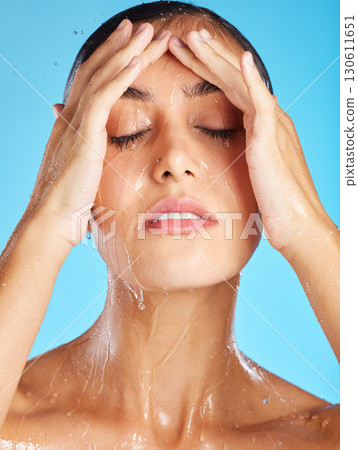 Woman, water and morning shower of a face for beauty, skincare and peace. Calm, relax and isolated young person doing wellness self care for skin glow with spa facial with blue studio background Woman, water and morning shower of a face for beauty, skincare and peace. Calm, relax and isolated young person doing wellness self care for skin glow with spa facial with blue studio background 130611651