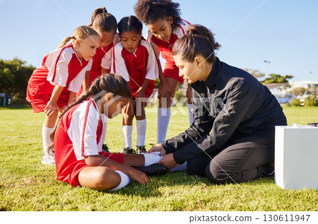 Sports, injury and children soccer team with their coach in a huddle helping a girl athlete. Fitness, training and kid with a sore, pain or muscle sprain after a match on an outdoor football field. Sports, injury and children soccer team with their coach in a huddle helping a girl athlete. Fitness, training and kid with a sore, pain or muscle sprain after a match on an outdoor football field. 130611947