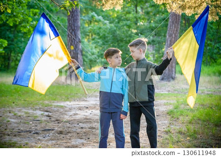 flags of Ukraine in hands of two boys. Children hold Ukrainian flags yellow and blue waving in wind . Ukraine's Independence Day. Flag Day 130611948