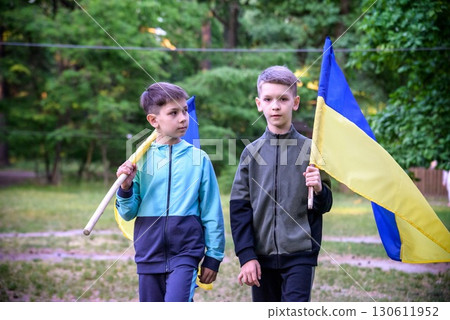 flags of Ukraine in hands of two boys. Children hold Ukrainian flags yellow and blue waving in wind . Ukraine's Independence Day. Flag Day 130611952