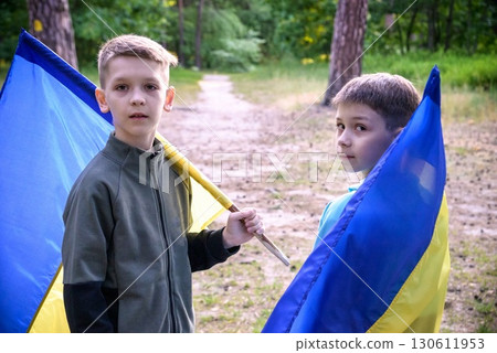 flags of Ukraine in hands of two boys. Children hold Ukrainian flags yellow and blue waving in wind . Ukraine's Independence Day. Flag Day 130611953
