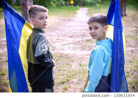 flags of Ukraine in hands of two boys. Children hold Ukrainian f flags of Ukraine in hands of two boys. Children hold Ukrainian f 130611954