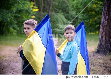 flags of Ukraine in hands of two boys. Children hold Ukrainian flags yellow and blue waving in wind . Ukraine's Independence Day. Flag Day flags of Ukraine in hands of two boys. Children hold Ukrainian flags yellow and blue waving in wind . Ukraine's Independence Day. Flag Day 130611956