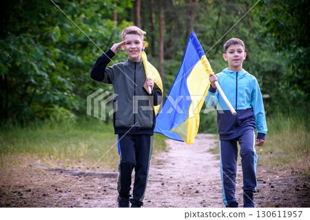 flags of Ukraine in hands of two boys. Children hold Ukrainian flags yellow and blue waving in wind . Ukraine's Independence Day. Flag Day 130611957