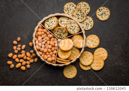 Various salty snacks in a round bowl on black table. Various salty snacks in a round bowl on black table. 130612045